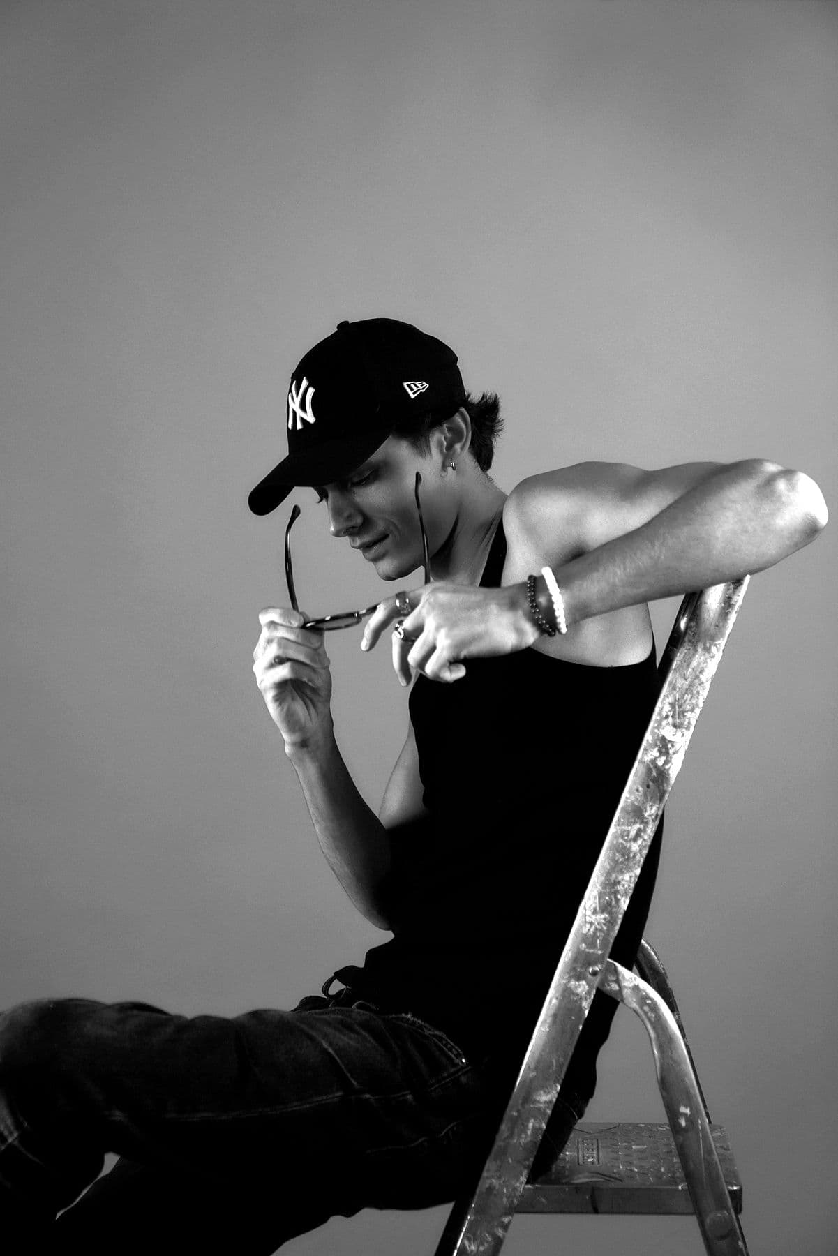 ONEYED seated on a metal stepladder, adjusting his cap