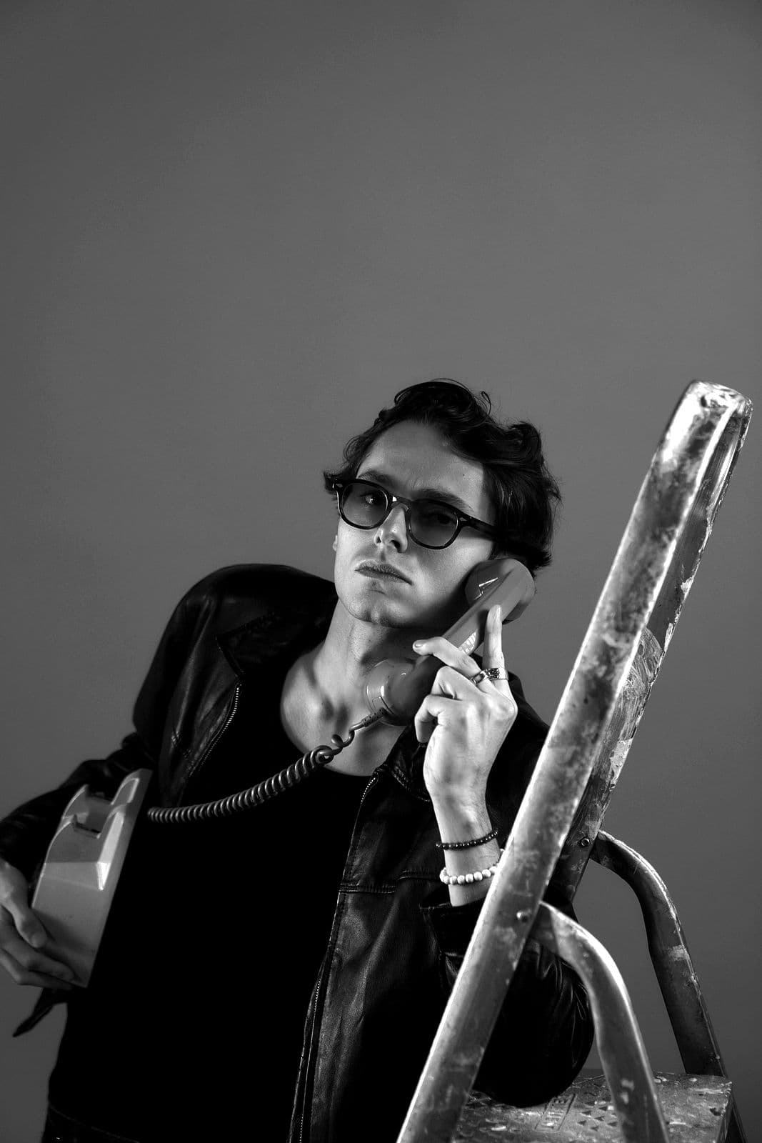 ONEYED in sunglasses, holding a vintage telephone receiver