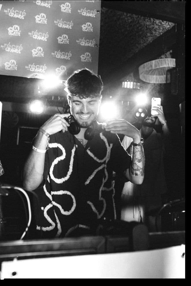 SMAILO smiling behind the decks, headphones around his neck